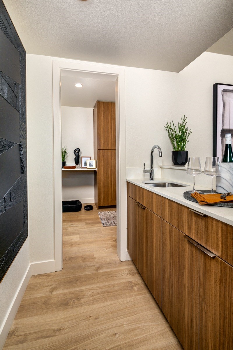A modern kitchen with wooden cabinets and a black fridge.