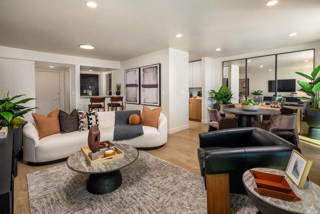 A modern living room with a white sofa, a coffee table, and a large mirror on the wall.