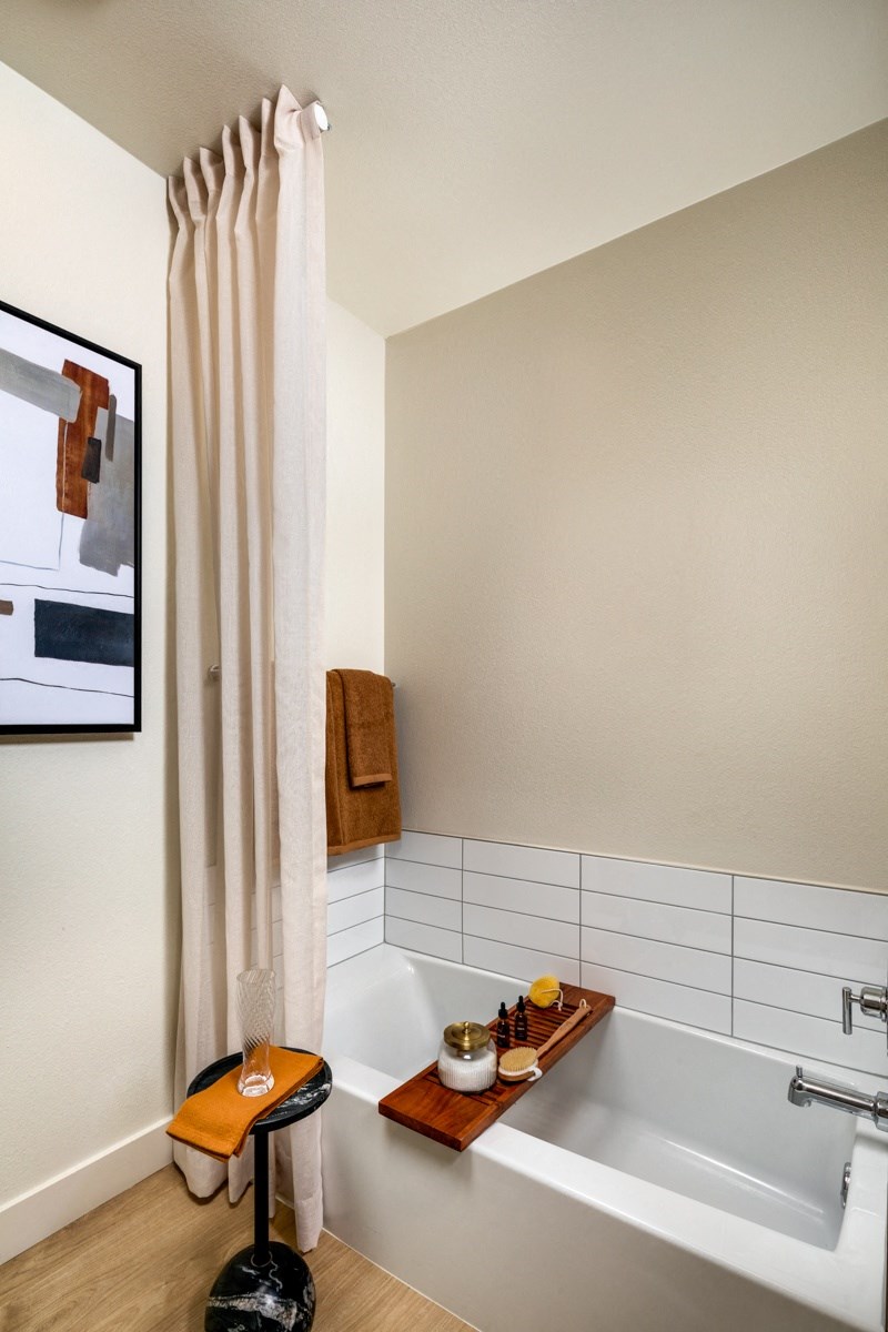 A bathroom with a white tub and a white shower curtain.