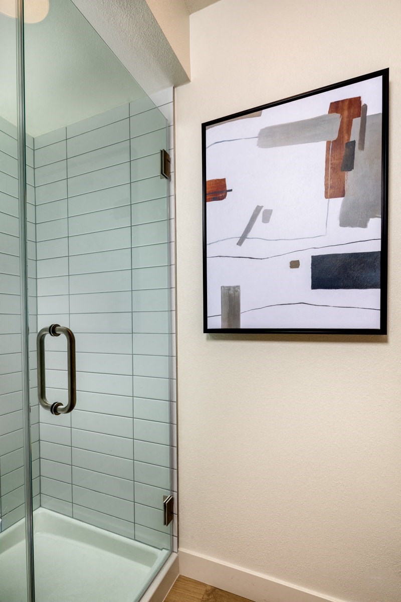 A bathroom with a glass shower and a picture on the wall.