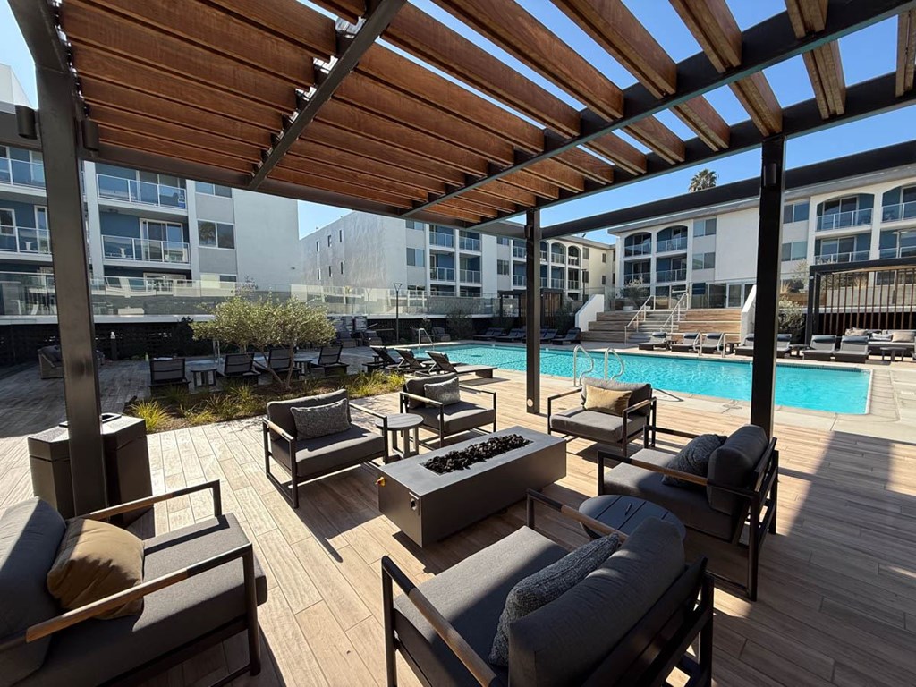 A wooden deck with couches and a pool in the background.