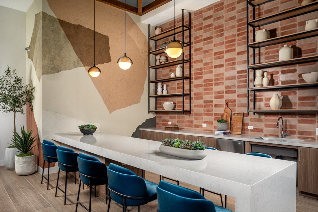 a kitchen with a long white table and blue chairs