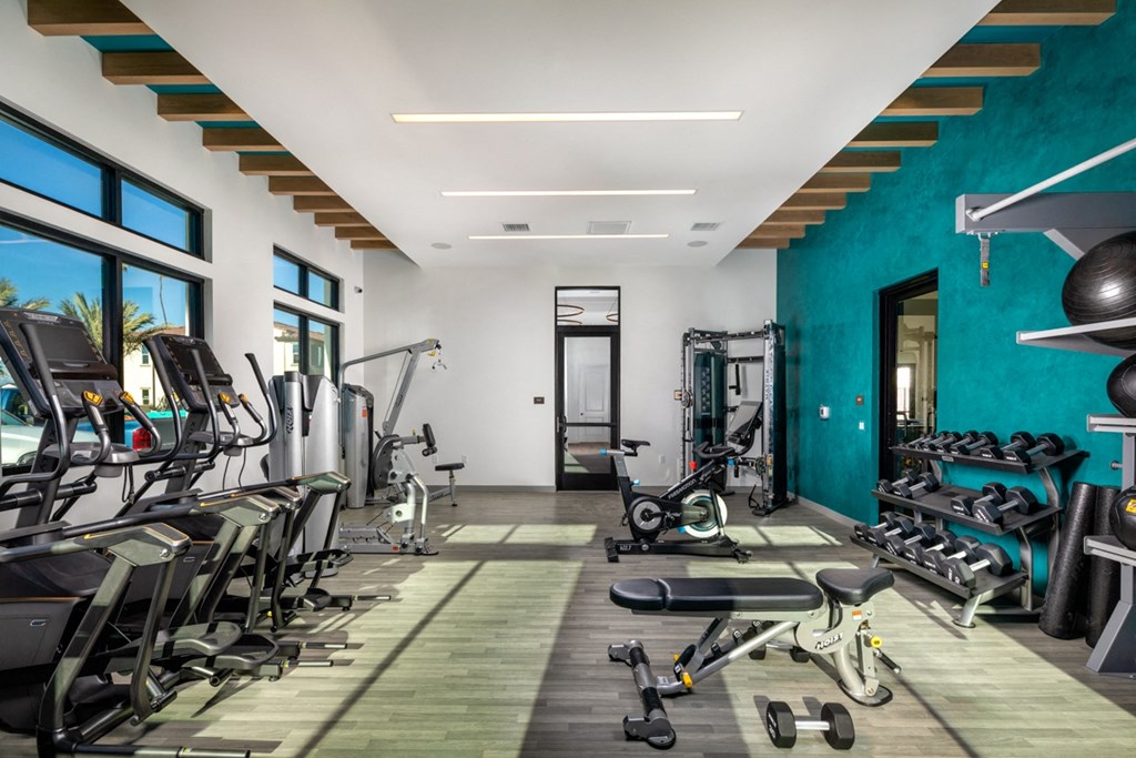 a gym with cardio equipment and a turquoise accent wall