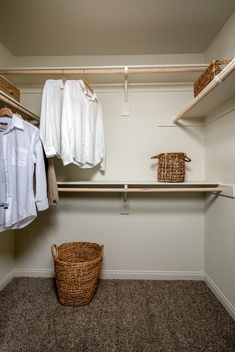 closet with white clothes and a wicker basket