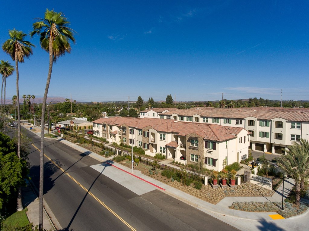 an aerial view of a row of apartment buildings with palm trees in the background