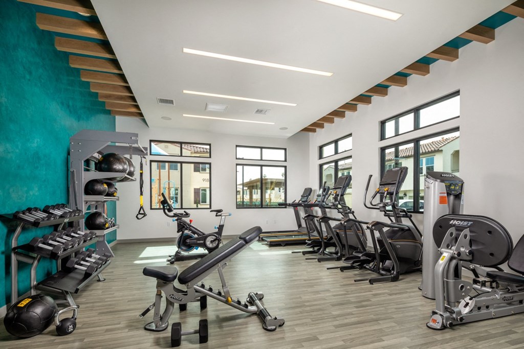 a gym with cardio equipment and a turquoise accent wall