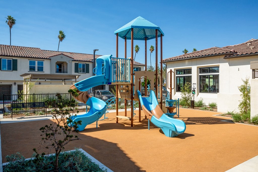 a playground with two slides and a swing set in front of a building
