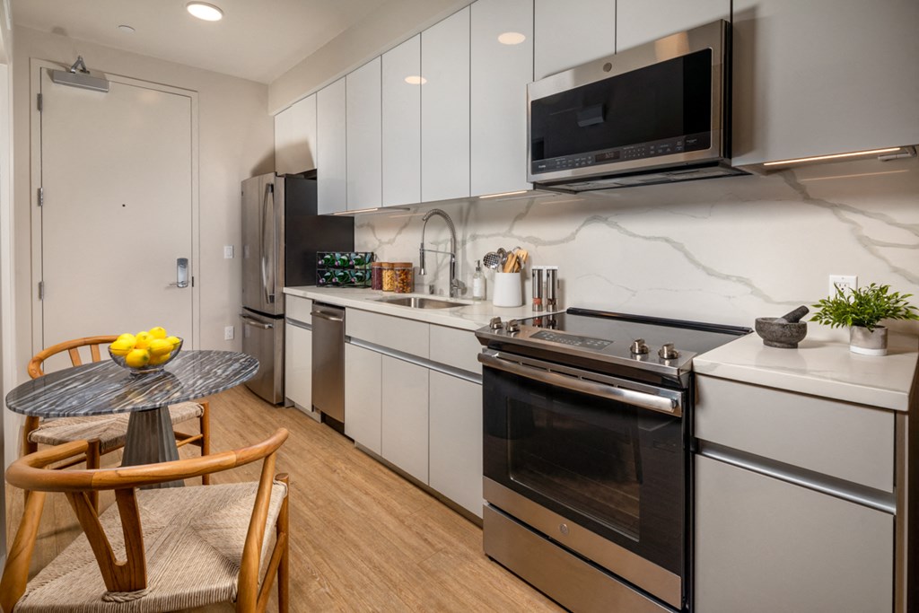 a kitchen with white cabinets and stainless steel appliances and a small table