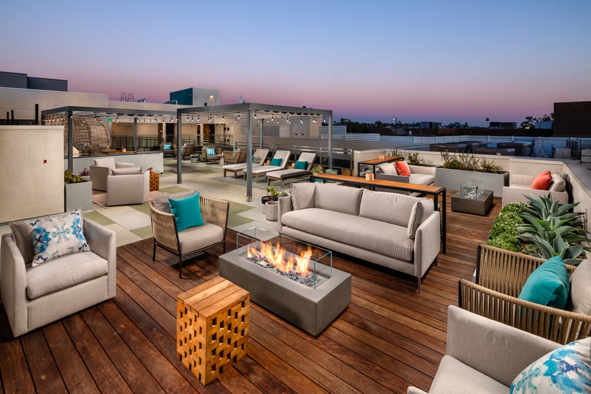 a roof top patio with couches and chairs and a fire pit