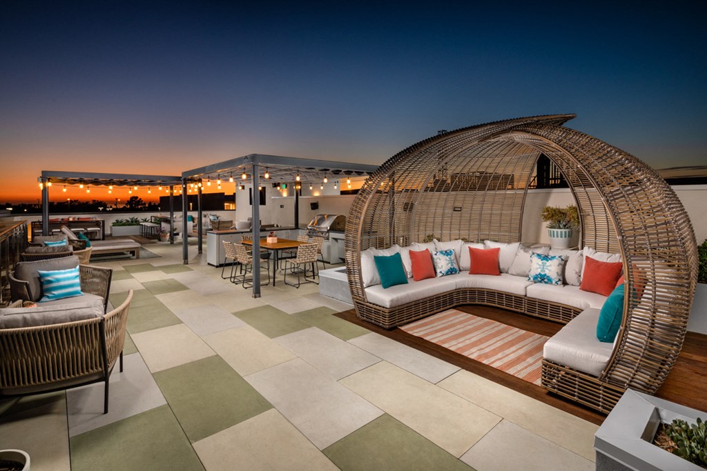 a patio with a swing chair and tables on a rooftop
