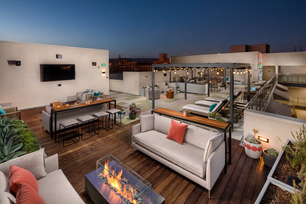 a rooftop terrace with couches and tables and a fireplace