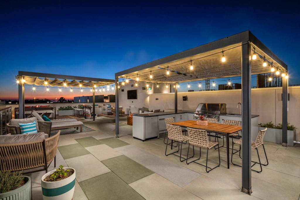 a rooftop patio with tables and chairs and a grill