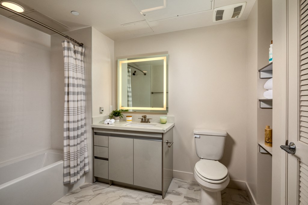 a bathroom with a toilet sink and shower and a mirror