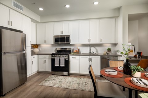 a kitchen and dining room with white cabinets and stainless steel appliances