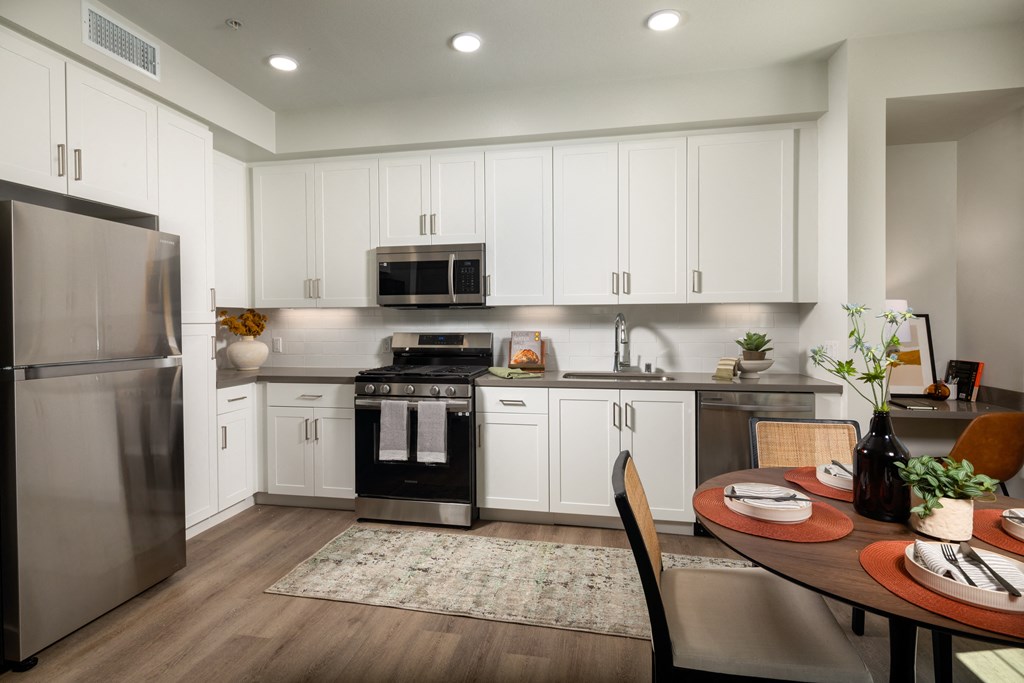a kitchen and dining room with white cabinets and stainless steel appliances
