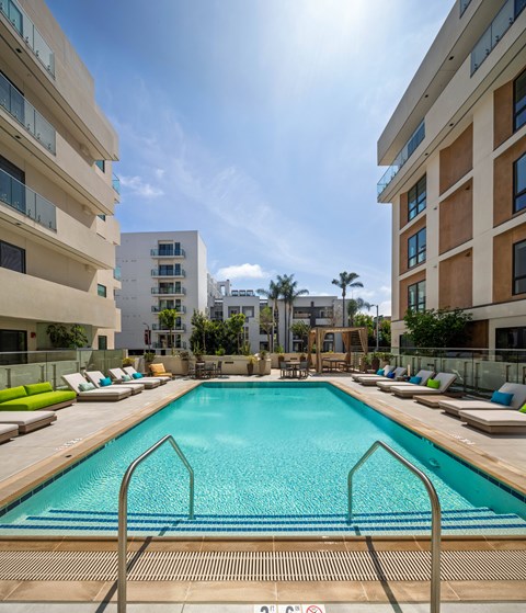 A swimming pool surrounded by lounge chairs and buildings.