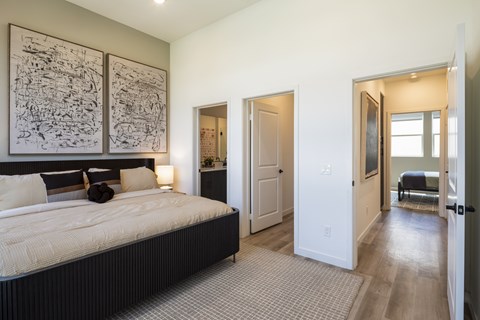 A bedroom with a large bed and two framed pictures on the wall.