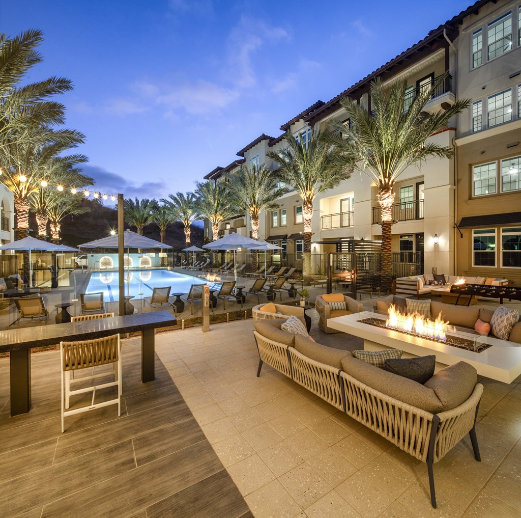A poolside patio with a fire pit and lounge chairs.