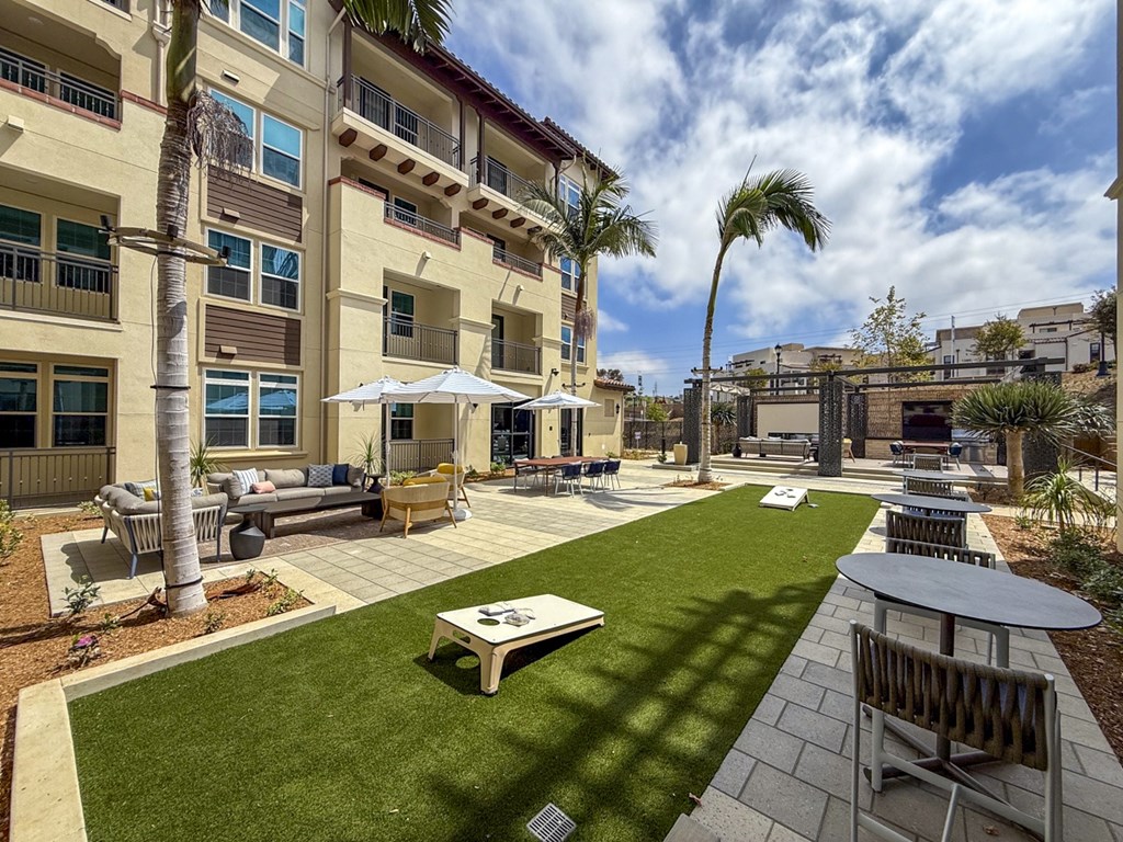 A sunny day at a residential complex with a well-maintained lawn and outdoor furniture.