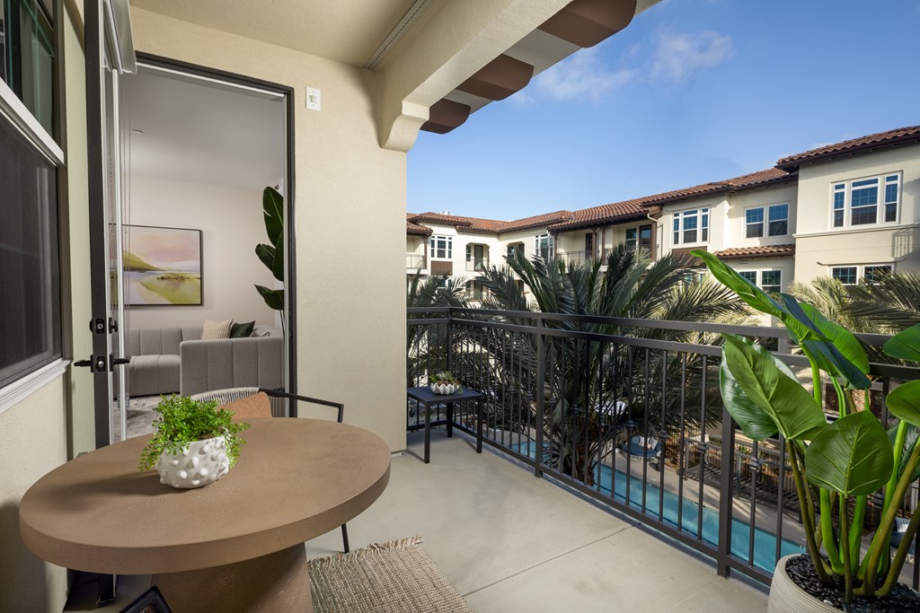 A balcony with a table and chairs overlooking a pool.