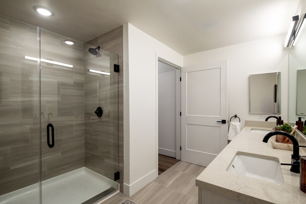 A modern bathroom with a walk-in shower and double sinks.