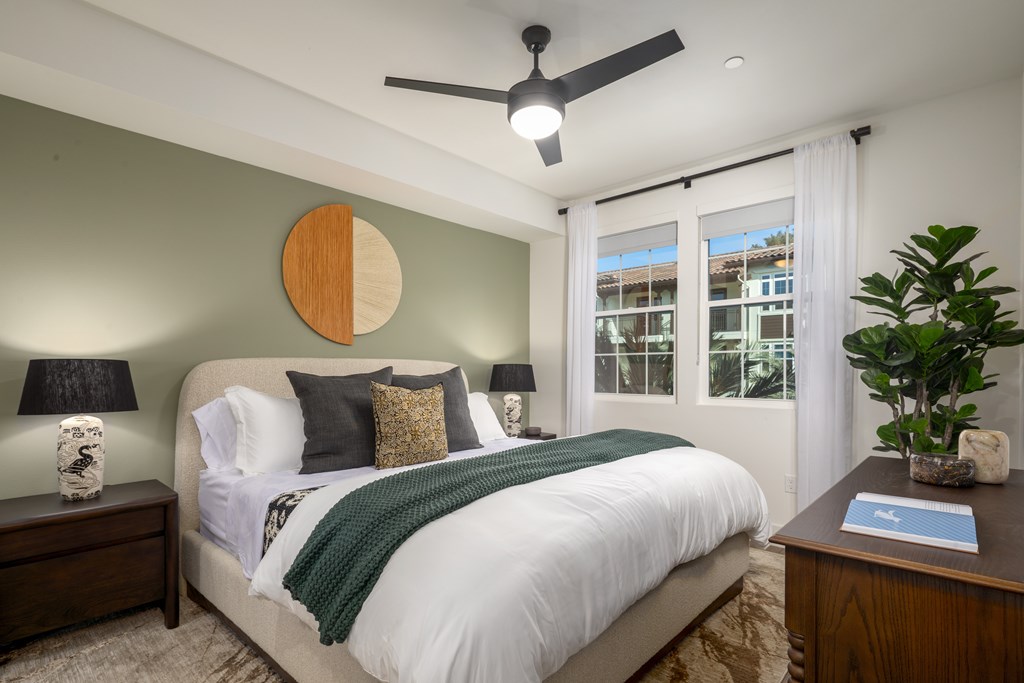 A bedroom with a bed, nightstands, and a ceiling fan.