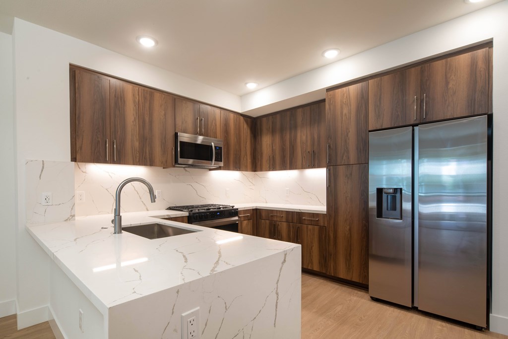 A modern kitchen with a marble countertop and stainless steel appliances.