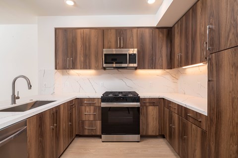 A modern kitchen with wooden cabinets and a black stove top oven.