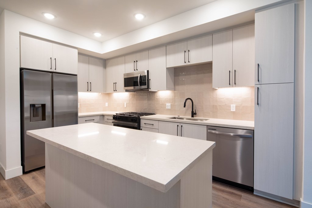 A modern kitchen with a white island and stainless steel appliances.