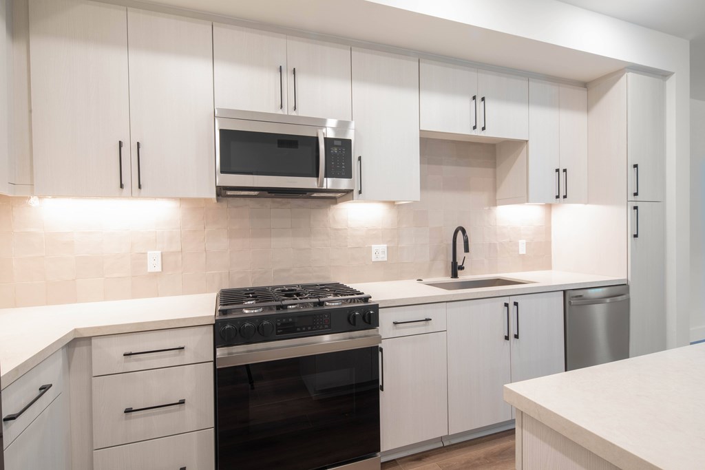 A kitchen with white cabinets and a black stove top.