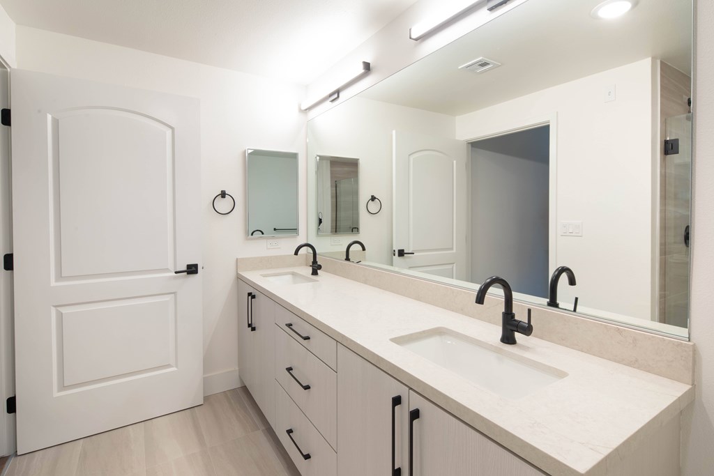A bathroom with a sink, mirrors and a door.
