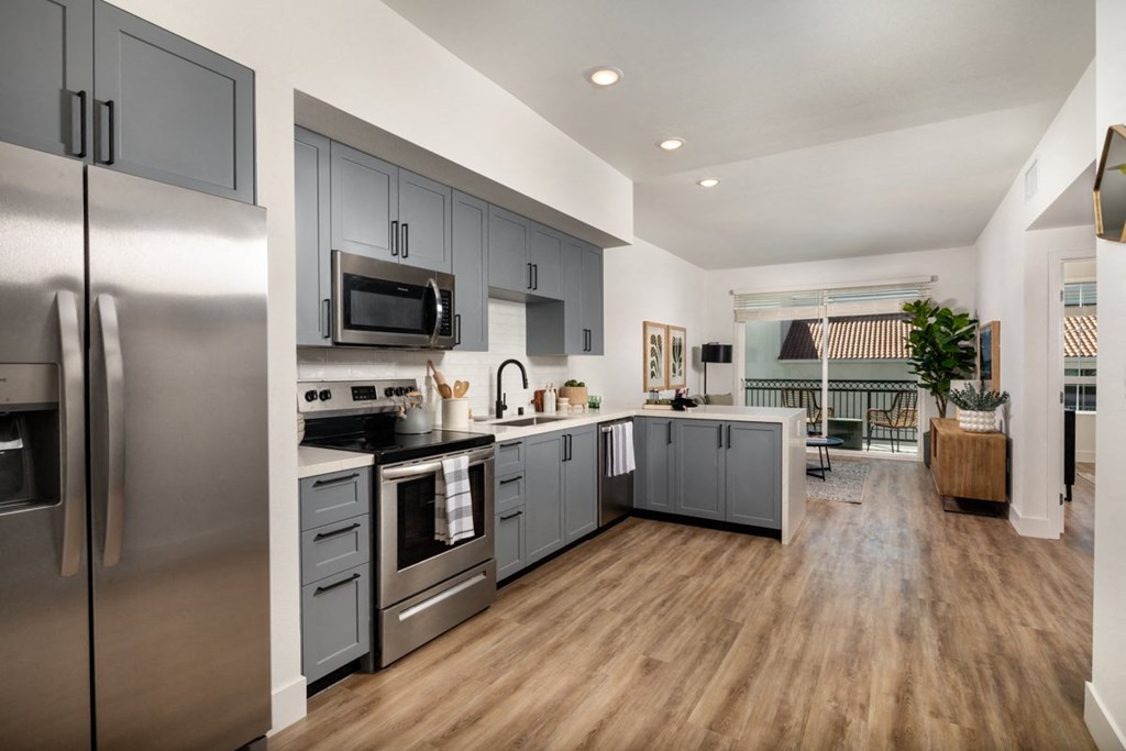an open kitchen with stainless steel appliances and gray cabinets