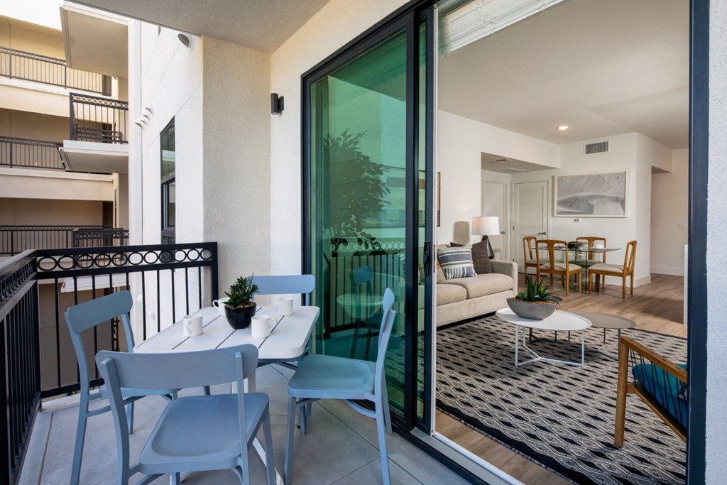 a balcony with a dining table and chairs and a living room