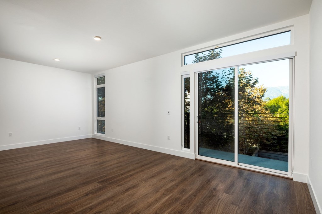 a living room with white walls and a large window and wooden floors