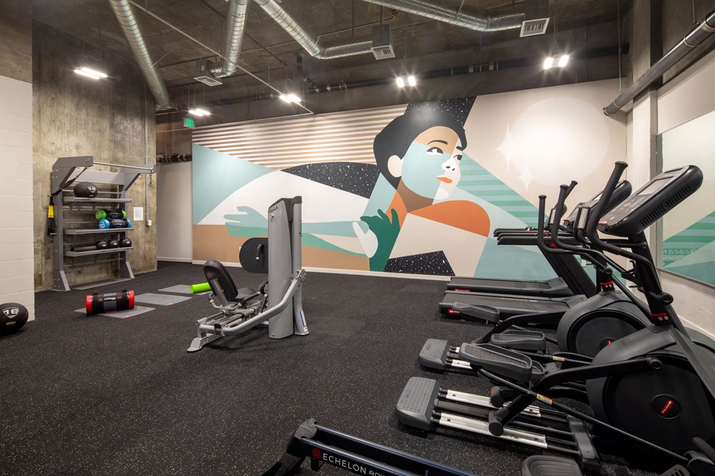 a gym with exercise equipment and a wall mural
