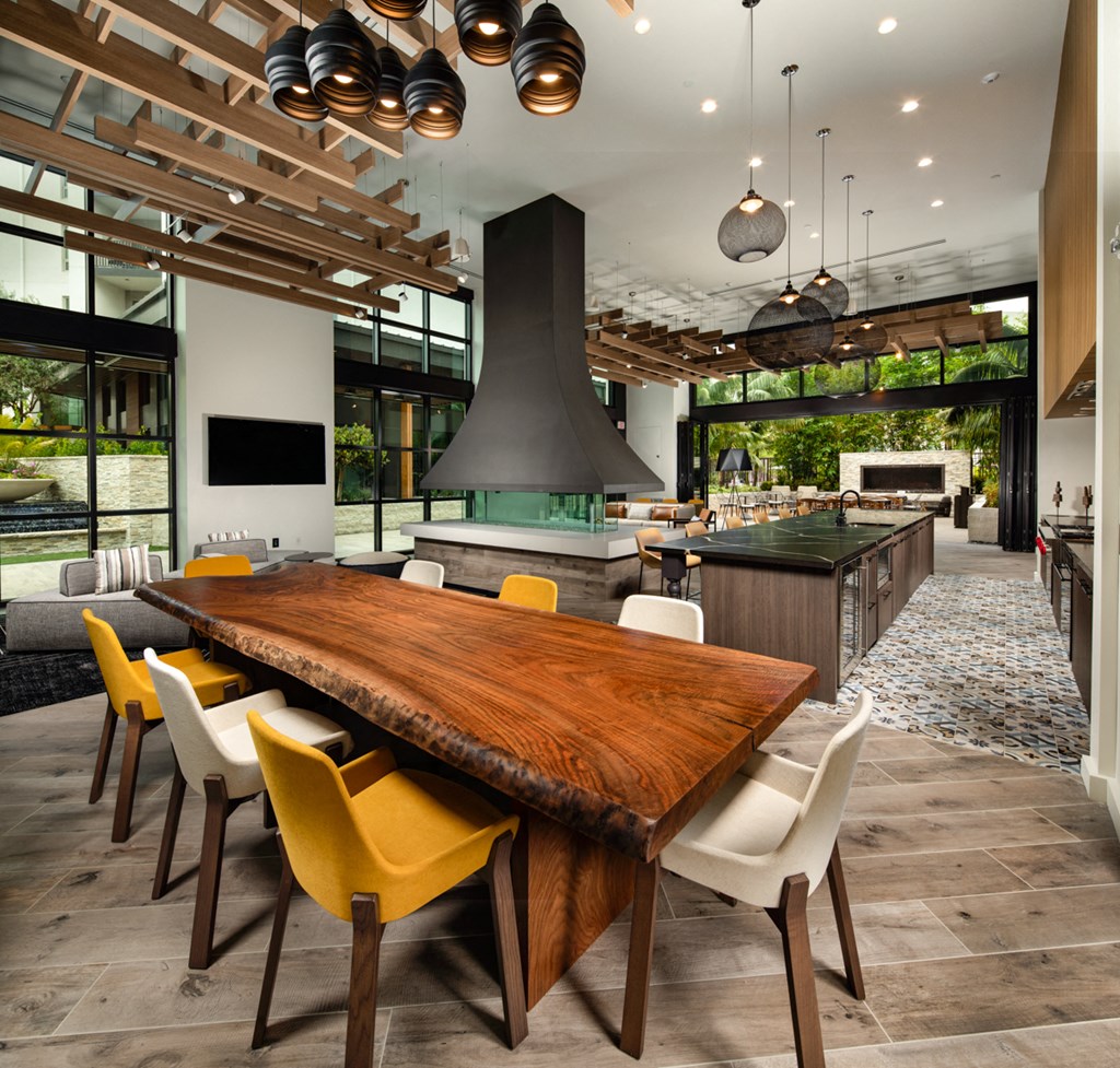 a large dining room and kitchen with a large wooden table and yellow chairs