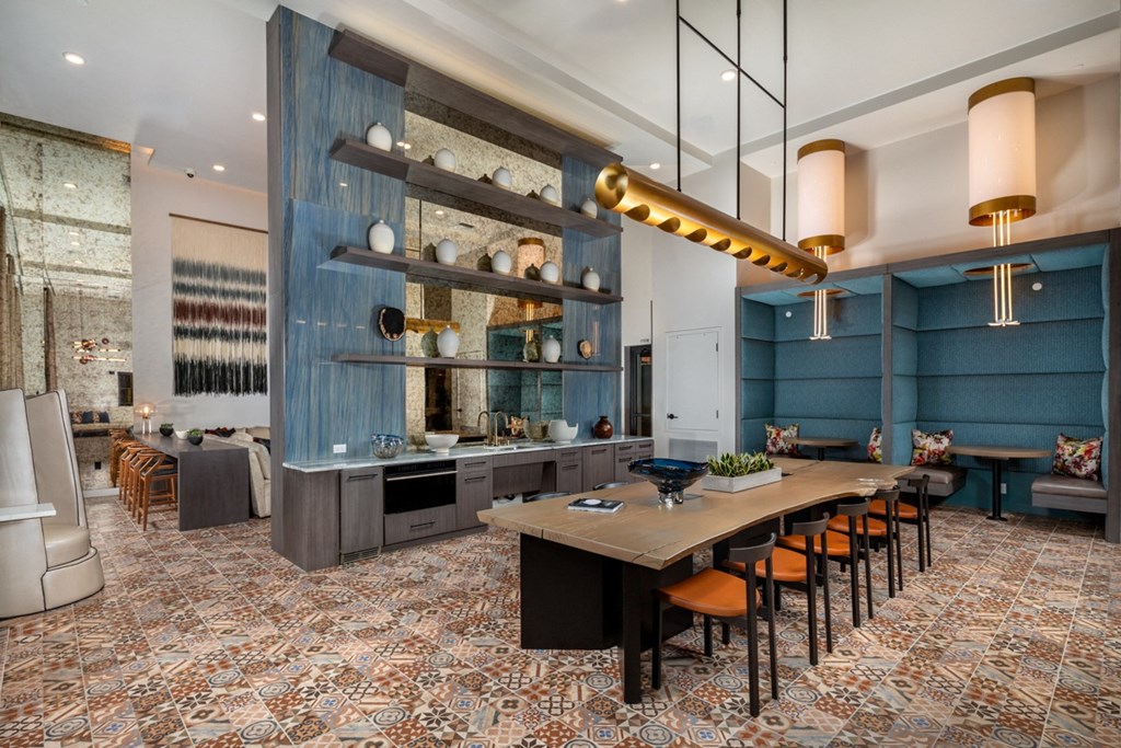 a dining room with a long table and chairs and a kitchen with blue walls