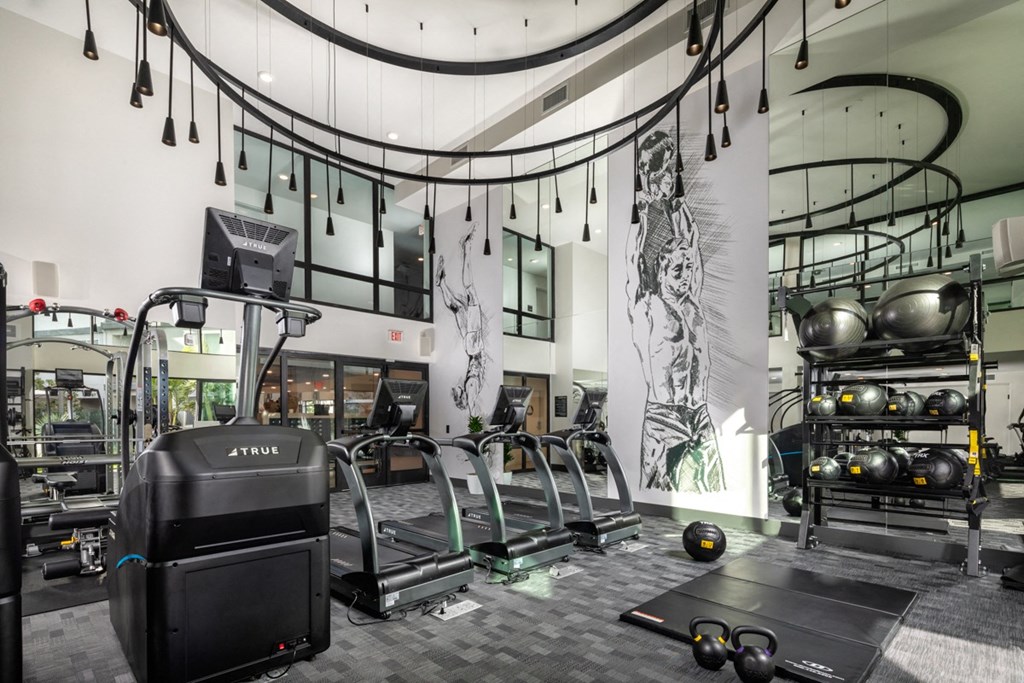 a gym with weights and other equipment in a building with glass walls