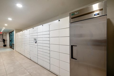 a set of white lockers in a hallway with a stainless steel refrigerator