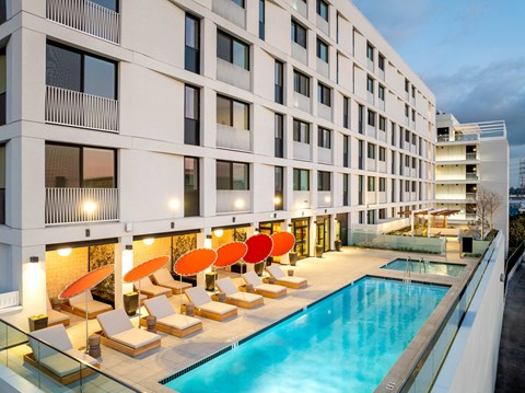 A modern building with a pool and loungers.