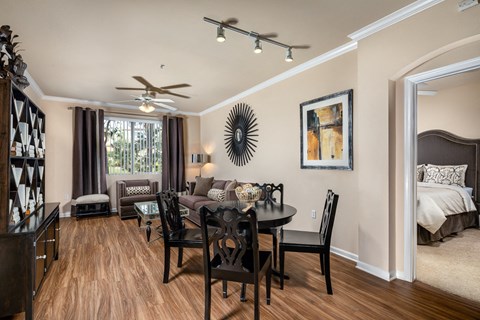 A dining room with a table set for two and a couch.