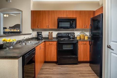 A kitchen with wooden cabinets and black appliances.