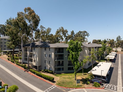 an aerial view of an apartment complex with trees and a street