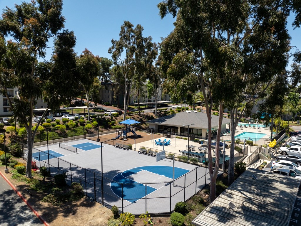 an aerial view of a tennis court and basketball court with pools and trees