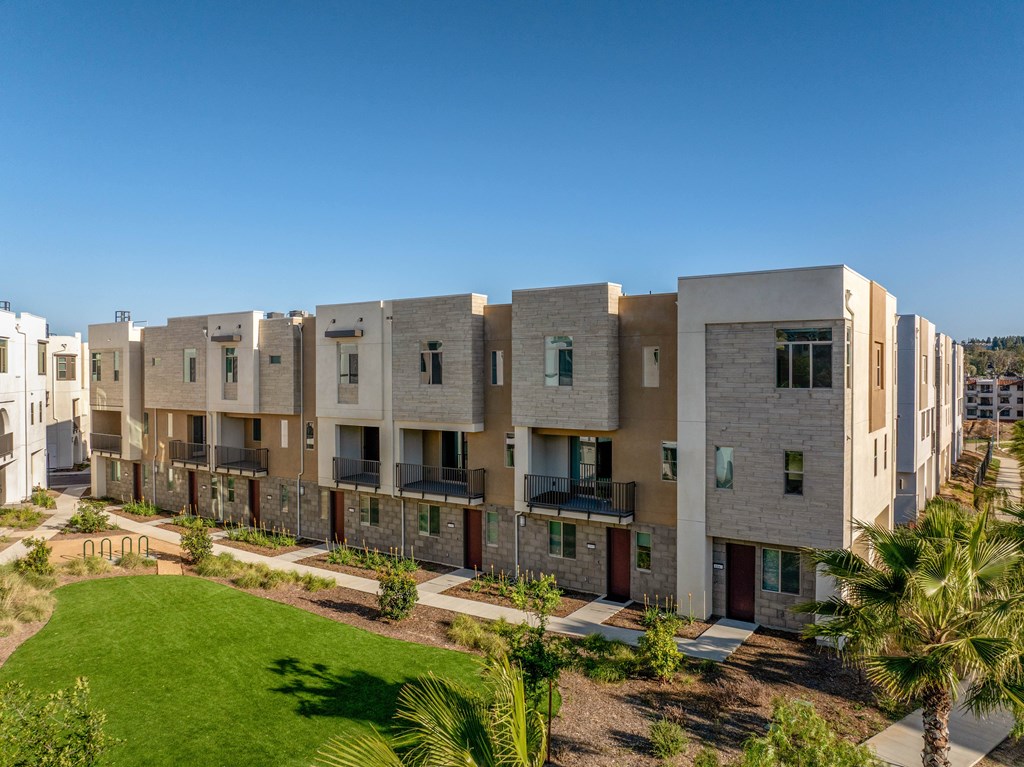 A row of modern apartment buildings with balconies and doors.