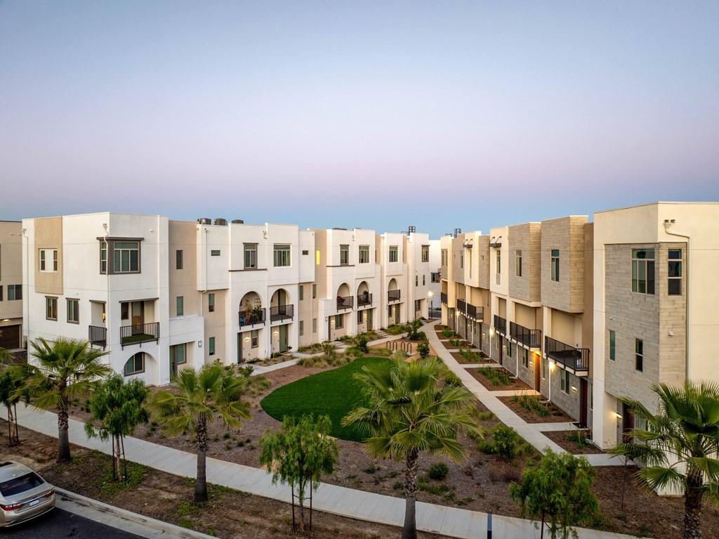 A row of modern apartment buildings with a car parked in front.
