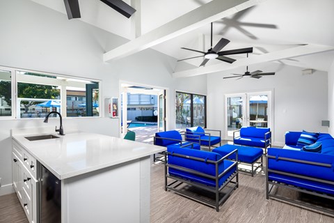 A modern kitchen with a white countertop and blue chairs.