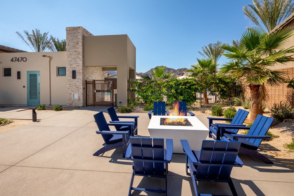 an outdoor patio with blue chairs and a fire pit