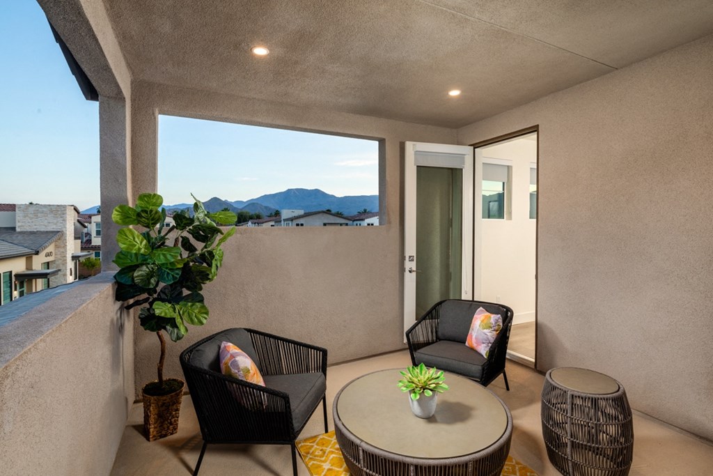a balcony with two chairs and a table with a plant