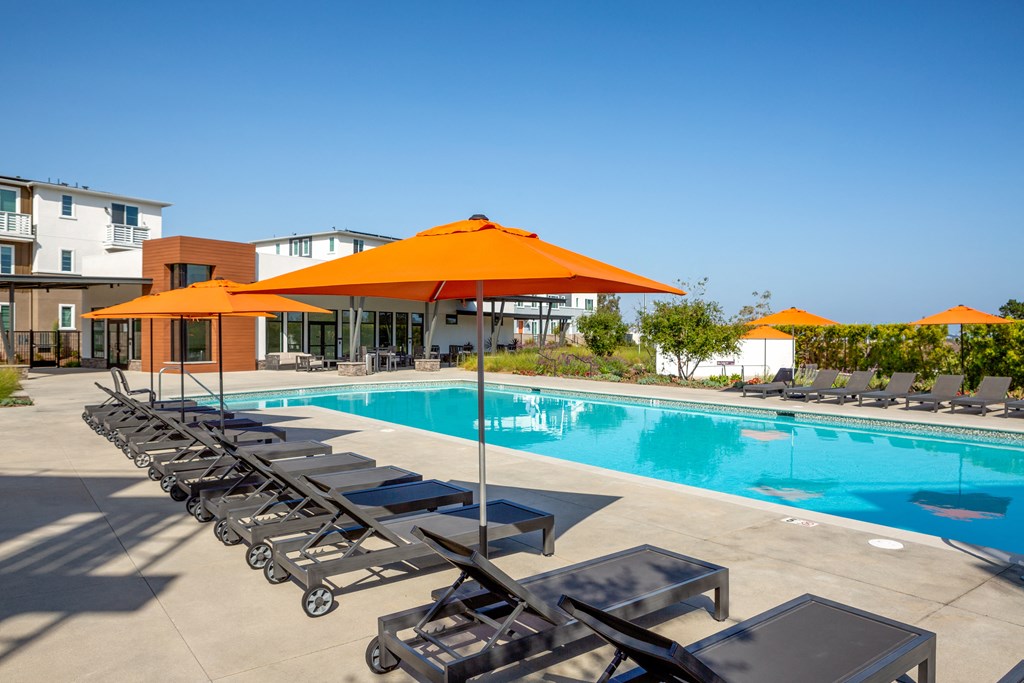 a swimming pool with orange umbrellas and chairs around it